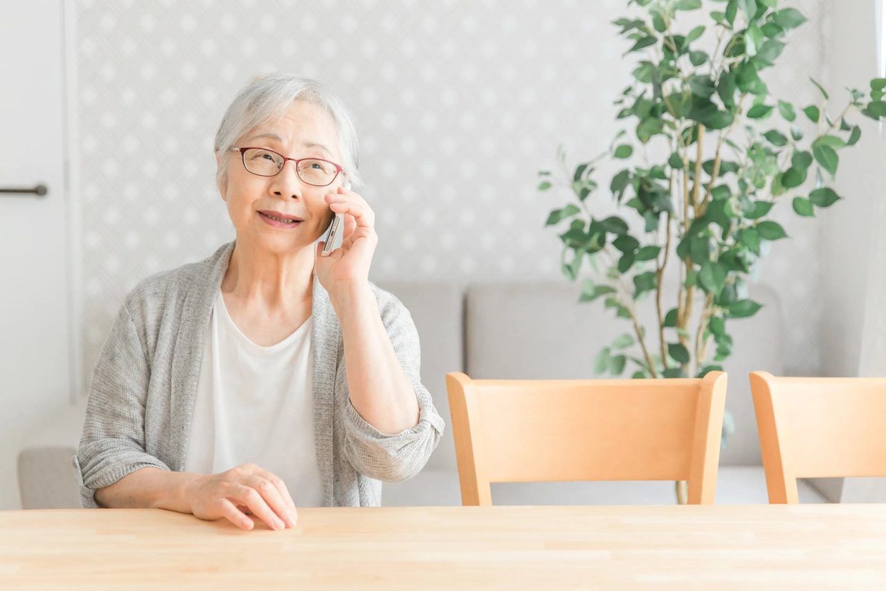 ダイニングで電話をしながら、穏やかに話すご高齢の女性