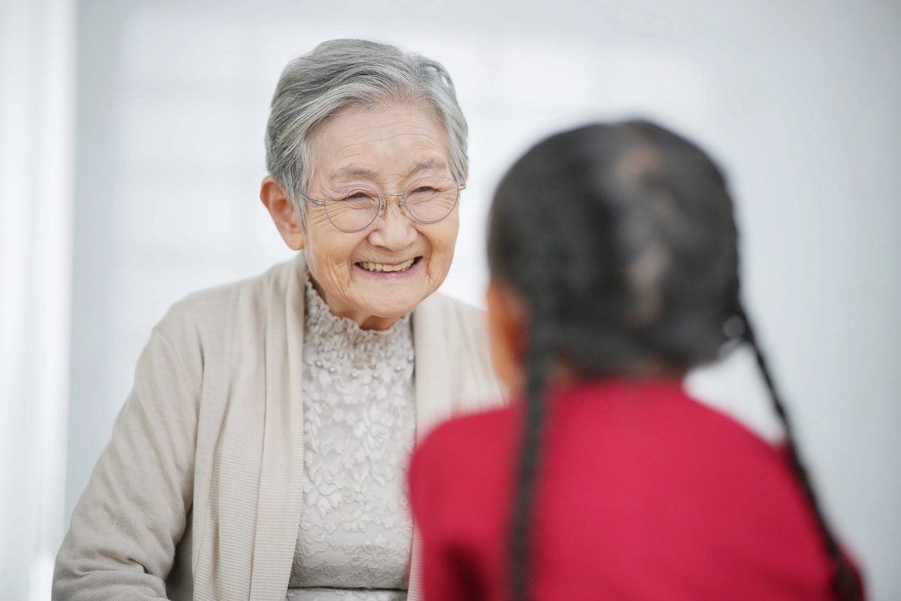 ご高齢の女性と、小さな女の子が寄り添っている場面