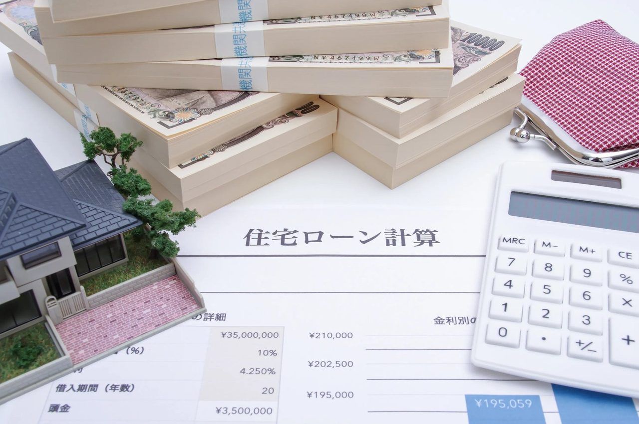 「住宅ローン計算」の書類と、おうちの模型、一万円札、電卓