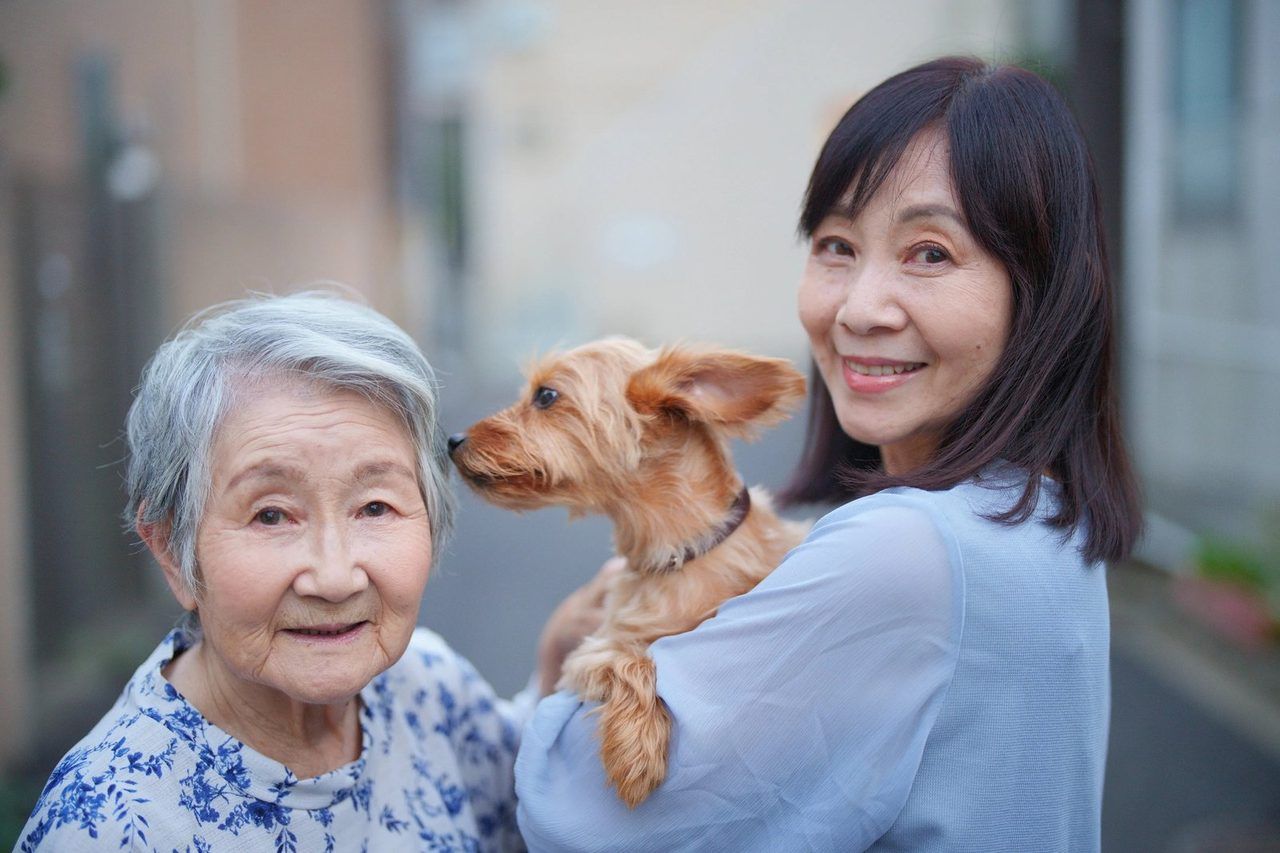 愛犬を抱いて、娘さんと笑顔で寄り添うご高齢の女性