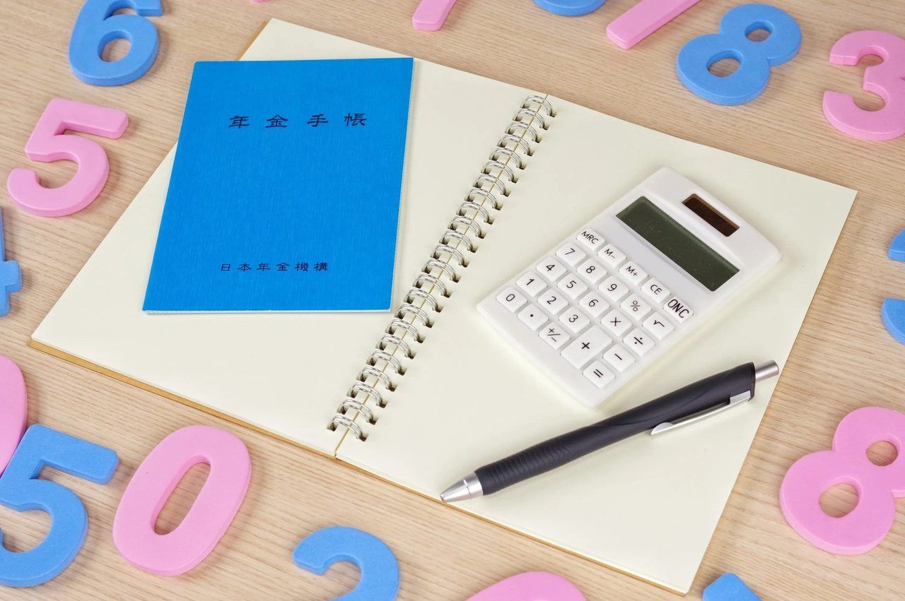 年金手帳と電卓、ノート、数字の積み木