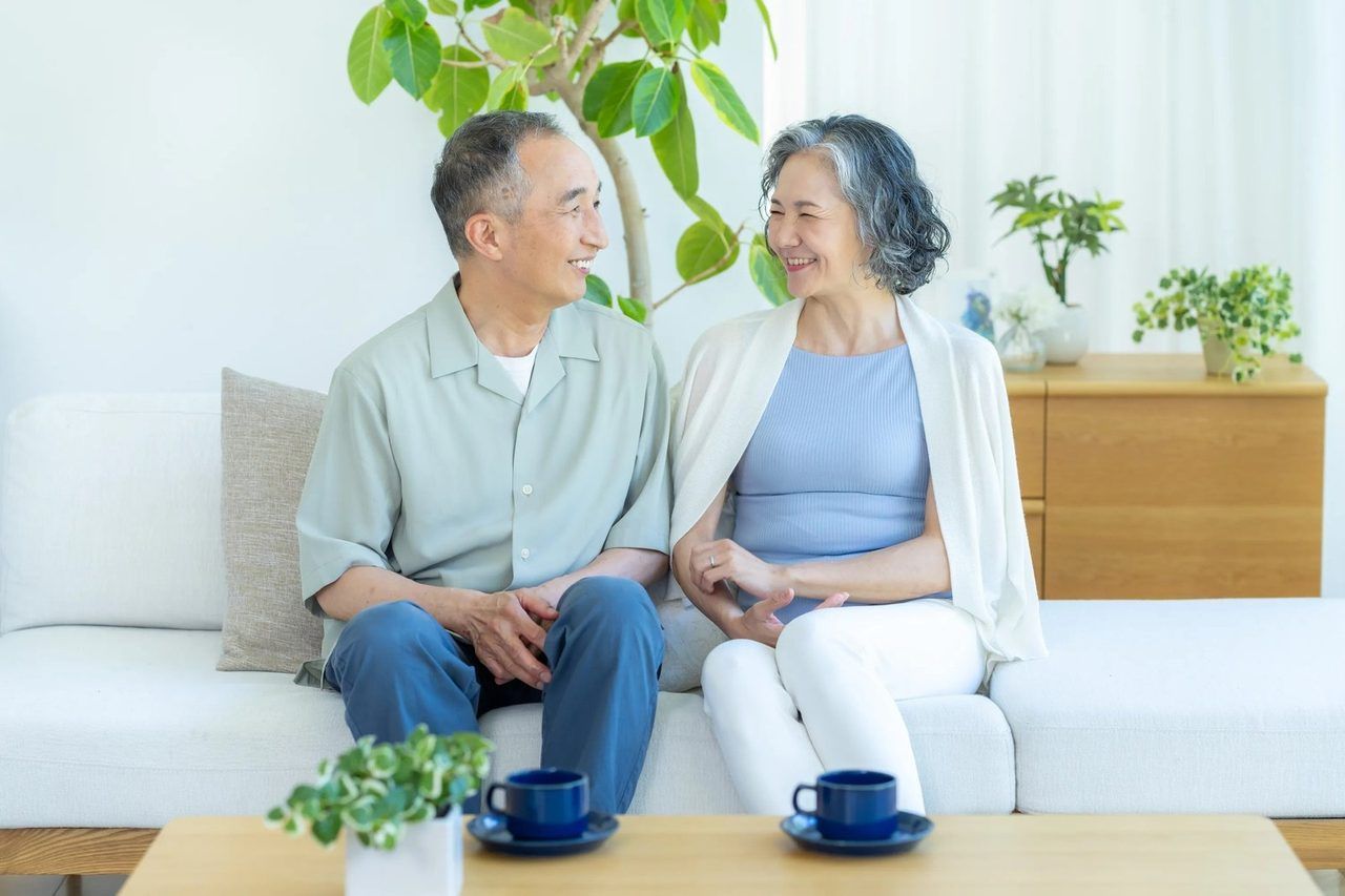 ご自宅のリビングで、穏やかに笑顔でくつろぐご夫婦