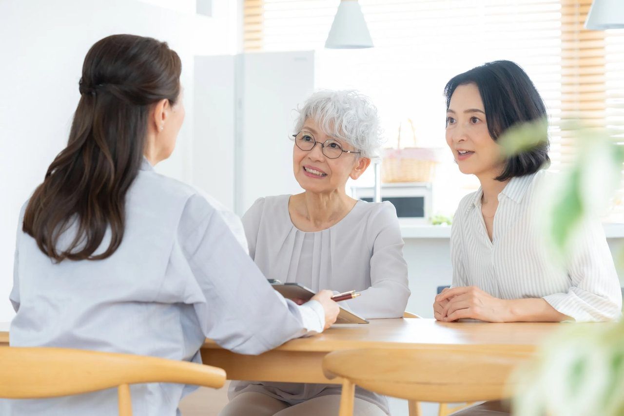 女性スタッフが、ご高齢の女性とそのご家族のお話を聞いている場面