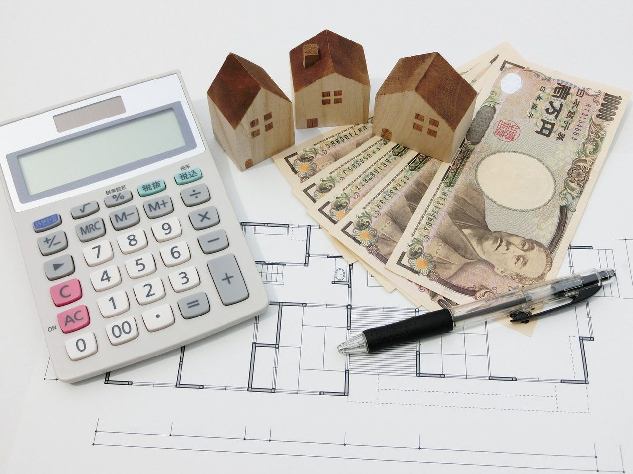 電卓と、おうちの模型、一万円札、間取り図