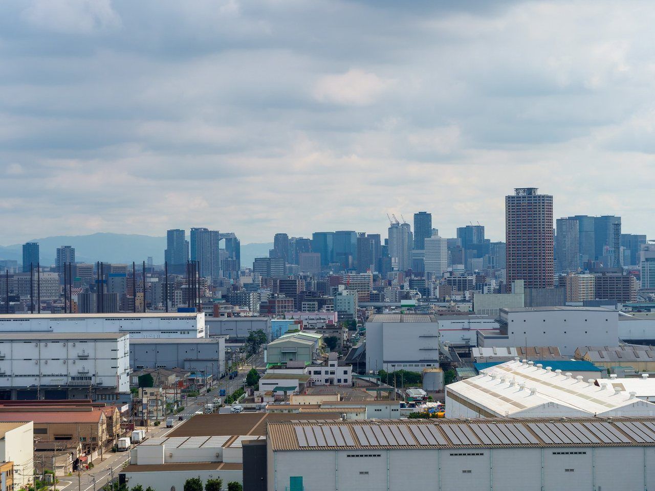 工場や住宅が広がる街並みと、遠くのビル群