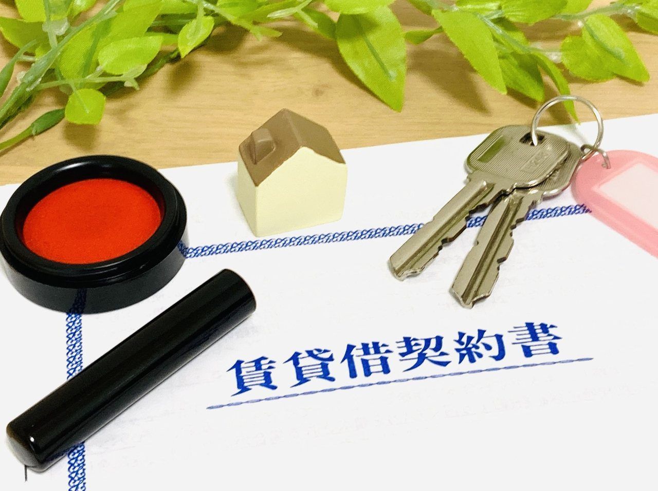賃貸借契約書と印鑑、鍵、家の置物